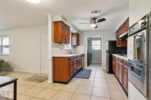 kitchen featuring appliances with stainless steel finishes, sink, light tile patterned flooring, ceiling fan, and ornamental molding