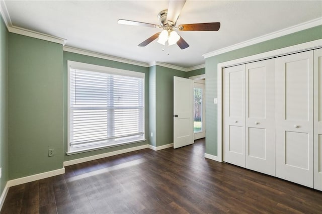 unfurnished bedroom featuring ceiling fan, dark hardwood / wood-style floors, crown molding, and a closet