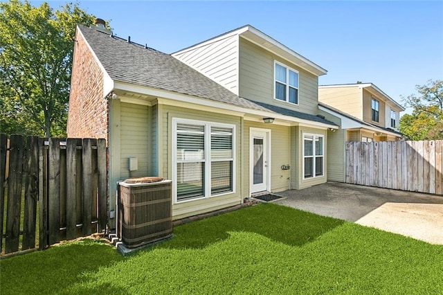 rear view of property featuring a lawn, a patio, and central AC unit