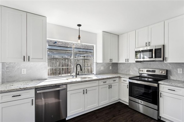 kitchen with appliances with stainless steel finishes, dark hardwood / wood-style flooring, sink, pendant lighting, and white cabinetry