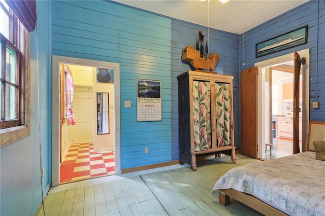 bedroom featuring light hardwood / wood-style floors, multiple windows, and wood walls