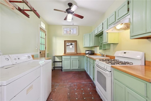 kitchen featuring white gas range, sink, green cabinetry, separate washer and dryer, and ceiling fan