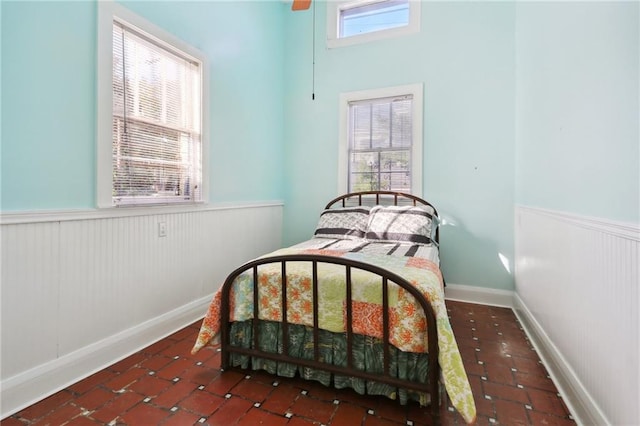 bedroom with multiple windows, dark tile patterned flooring, and ceiling fan