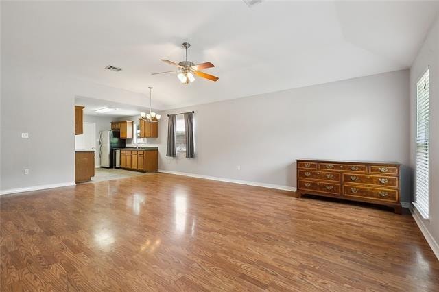 unfurnished living room with hardwood / wood-style flooring and ceiling fan with notable chandelier