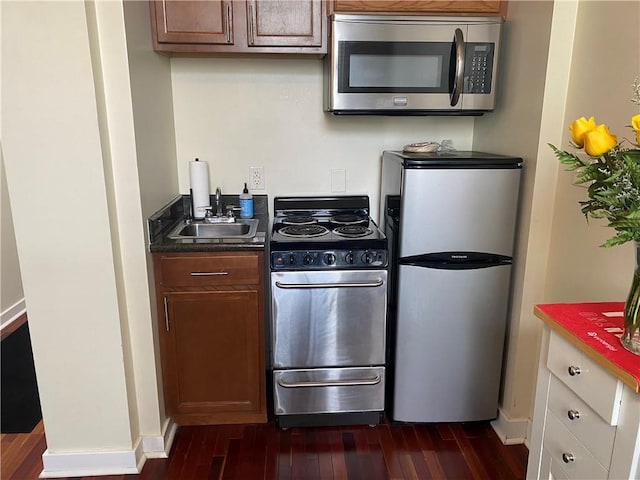 kitchen with appliances with stainless steel finishes, sink, and dark hardwood / wood-style floors