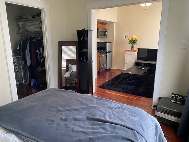 bedroom featuring stainless steel fridge, a spacious closet, dark wood-type flooring, and a closet