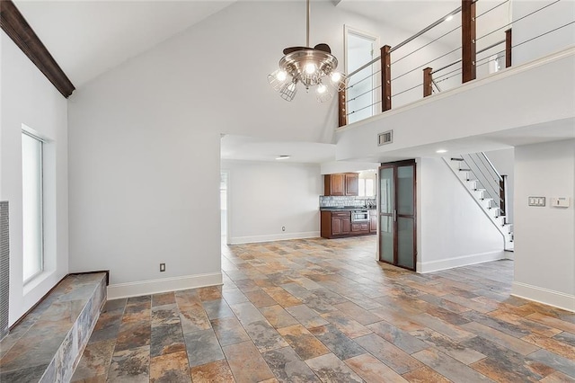 unfurnished living room with a chandelier and high vaulted ceiling