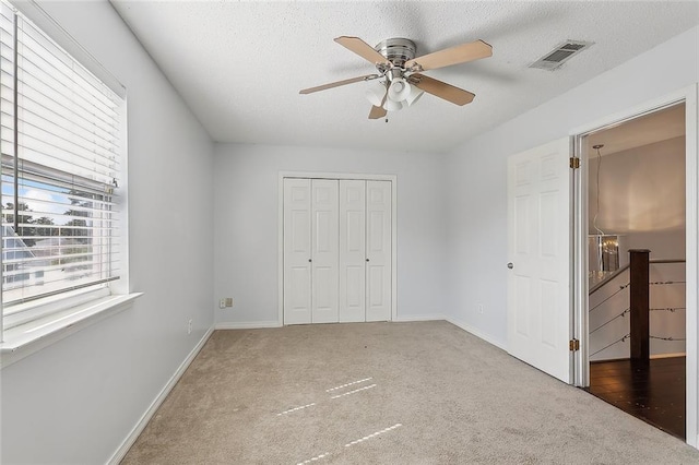 unfurnished bedroom with a closet, ceiling fan, a textured ceiling, and carpet floors