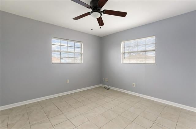 tiled empty room with ceiling fan and a healthy amount of sunlight