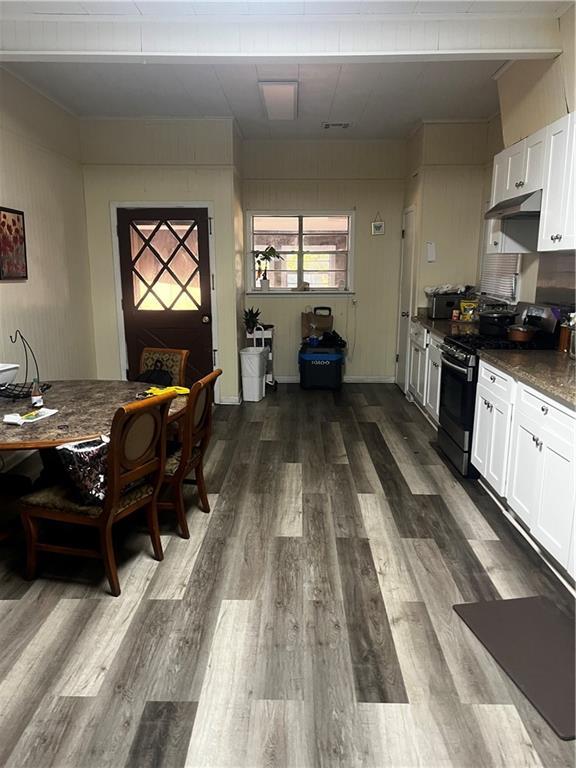 kitchen with stainless steel electric stove, white cabinetry, wood-type flooring, and dark stone counters