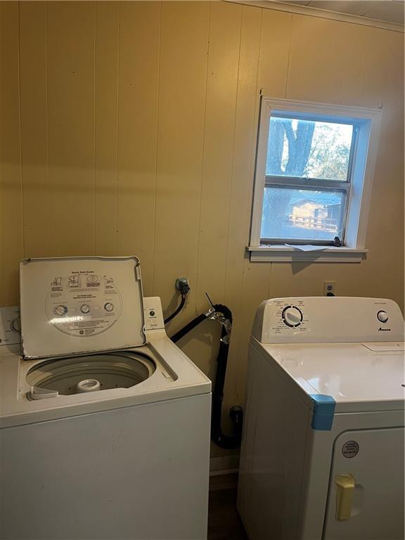 clothes washing area with wooden walls and separate washer and dryer