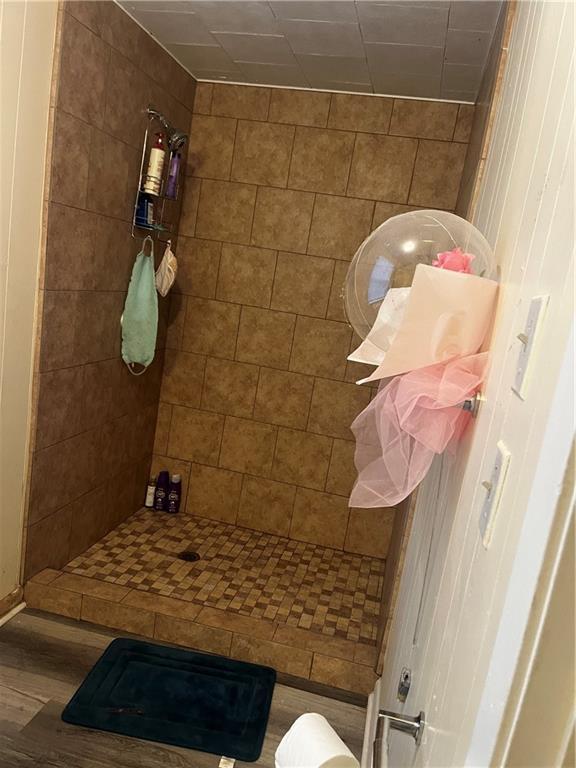 bathroom with a tile shower and hardwood / wood-style flooring