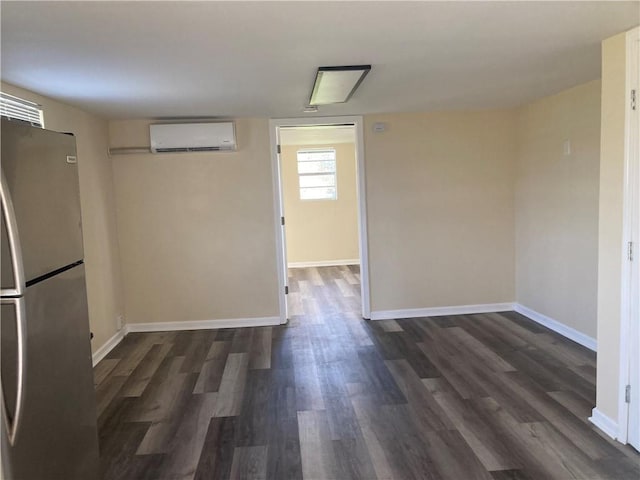 spare room featuring dark wood-type flooring and an AC wall unit