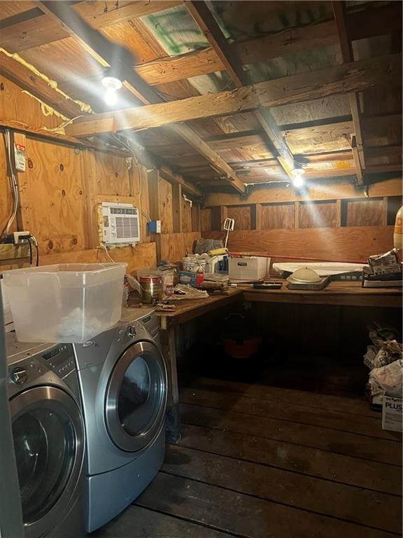 clothes washing area featuring wooden walls, a wall mounted AC, washer and clothes dryer, and a workshop area