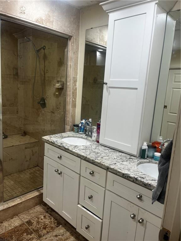 bathroom featuring tiled shower and vanity