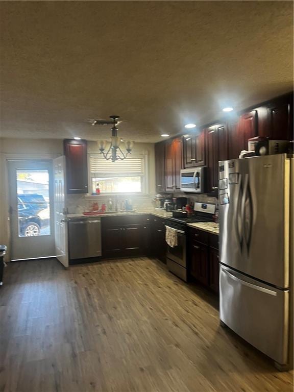 kitchen featuring tasteful backsplash, a chandelier, stainless steel appliances, and hardwood / wood-style flooring