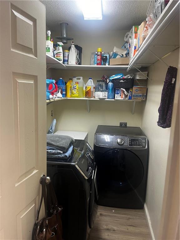 laundry area featuring hardwood / wood-style flooring, a textured ceiling, and independent washer and dryer