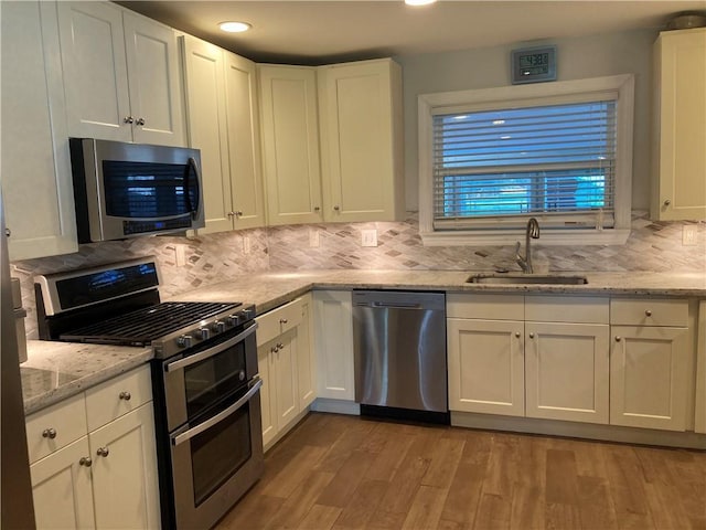 kitchen featuring sink, white cabinets, light hardwood / wood-style floors, and appliances with stainless steel finishes