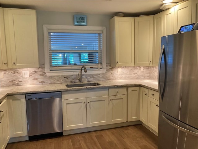 kitchen with dark wood-type flooring, sink, light stone countertops, white cabinetry, and stainless steel appliances