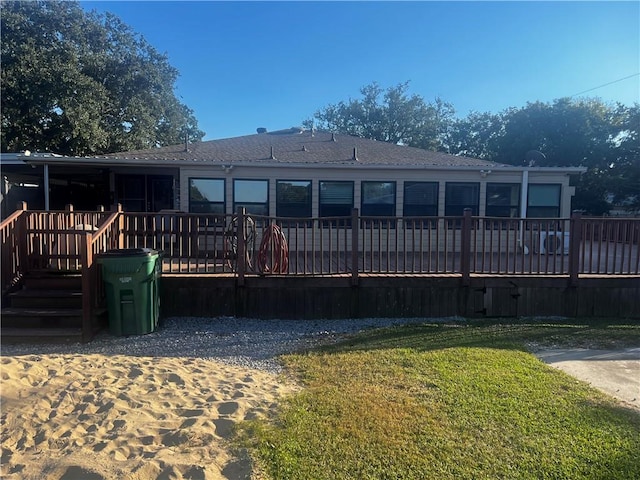 back of property with a wooden deck and a yard