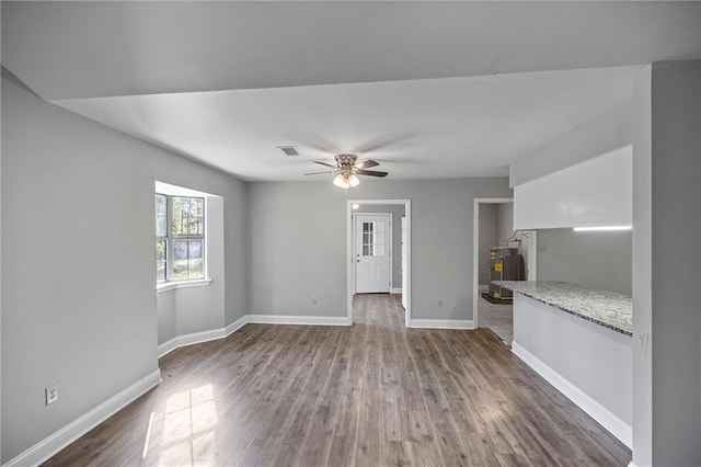 unfurnished living room featuring ceiling fan, dark hardwood / wood-style flooring, and water heater