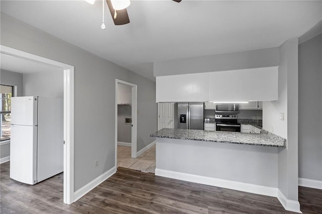 kitchen with kitchen peninsula, appliances with stainless steel finishes, dark hardwood / wood-style flooring, and white cabinetry