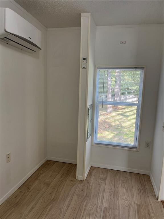 doorway featuring a textured ceiling, a wall mounted air conditioner, and light wood-type flooring