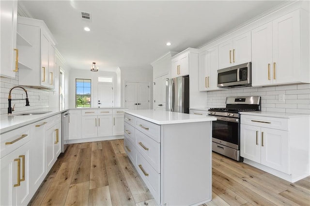 kitchen featuring appliances with stainless steel finishes, light wood-type flooring, white cabinetry, and sink