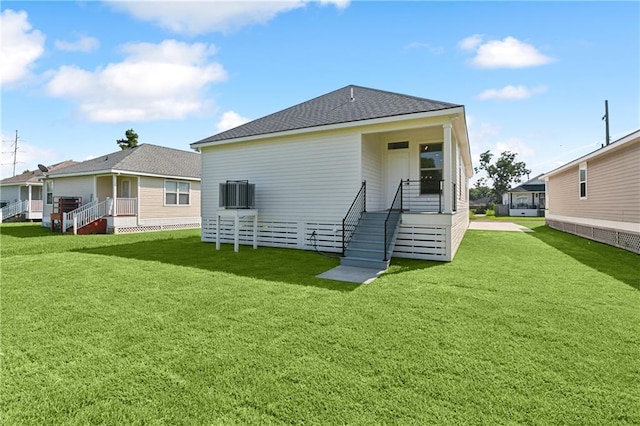 rear view of house featuring a lawn and central AC