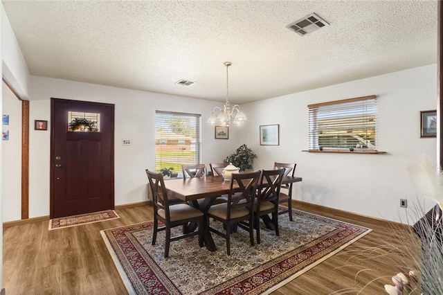 dining room featuring an inviting chandelier, a textured ceiling, and wood-type flooring