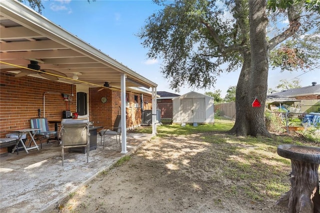 view of yard featuring a storage unit, a patio area, and ceiling fan