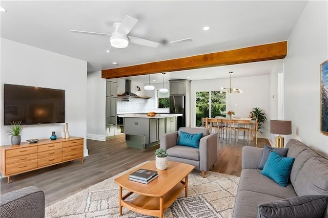 living room featuring dark hardwood / wood-style flooring, beamed ceiling, and ceiling fan with notable chandelier