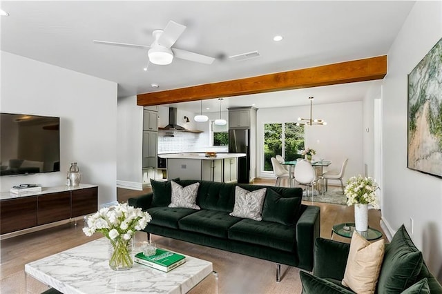 living room featuring ceiling fan with notable chandelier, light hardwood / wood-style floors, and beam ceiling