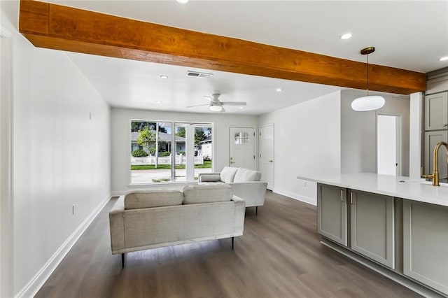 living room with beamed ceiling, ceiling fan, dark wood-type flooring, and sink