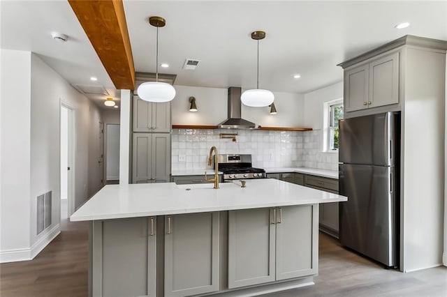 kitchen with gray cabinets, wall chimney exhaust hood, wood-type flooring, and appliances with stainless steel finishes