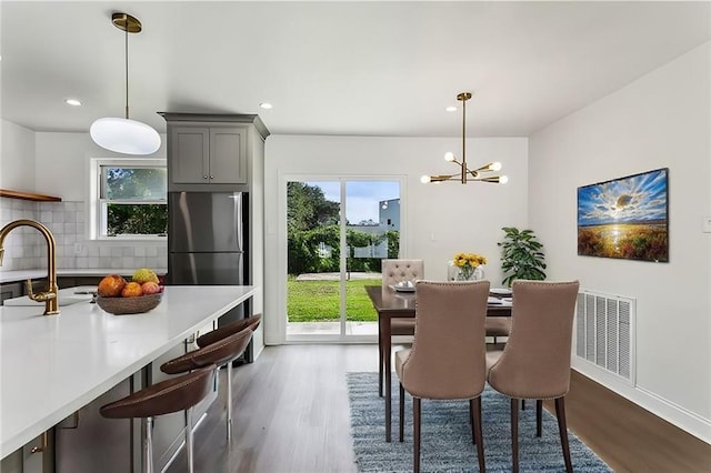 dining area with dark hardwood / wood-style flooring, a healthy amount of sunlight, and an inviting chandelier