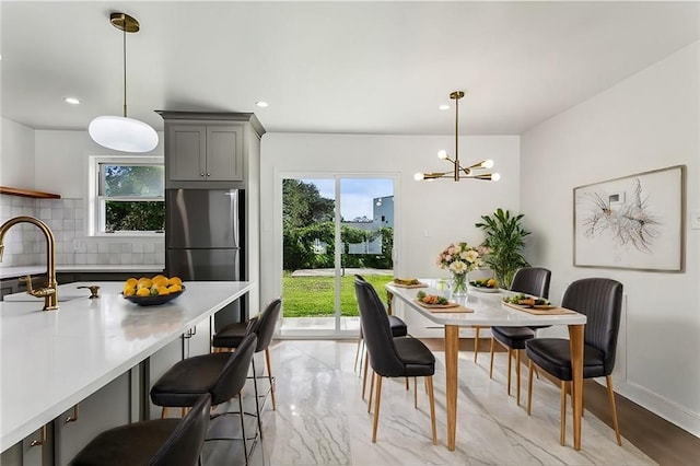 dining space with sink, a wealth of natural light, and an inviting chandelier