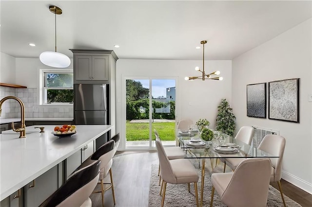 dining space with a chandelier, plenty of natural light, dark wood-type flooring, and sink