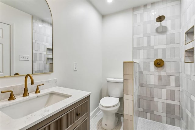 bathroom with tile patterned flooring, toilet, vanity, and tiled shower