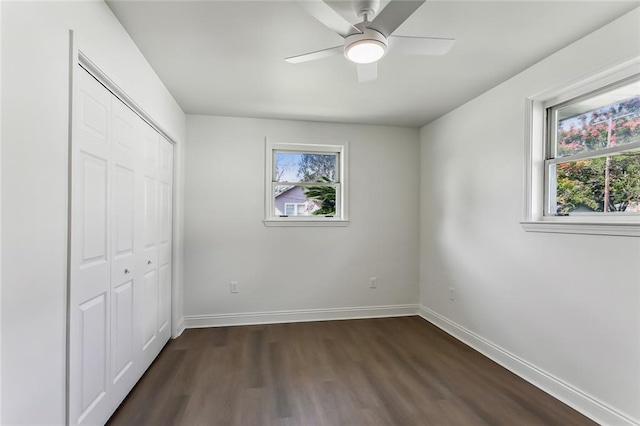 unfurnished bedroom featuring ceiling fan, a closet, dark hardwood / wood-style flooring, and multiple windows