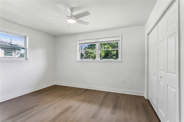 unfurnished bedroom featuring ceiling fan, a closet, and dark wood-type flooring