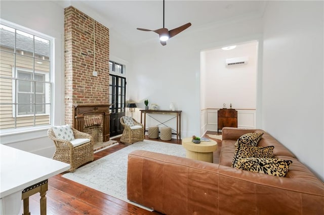 living room with a brick fireplace, hardwood / wood-style flooring, a healthy amount of sunlight, and ceiling fan