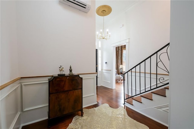 entrance foyer featuring an inviting chandelier, a wall mounted AC, and dark hardwood / wood-style flooring