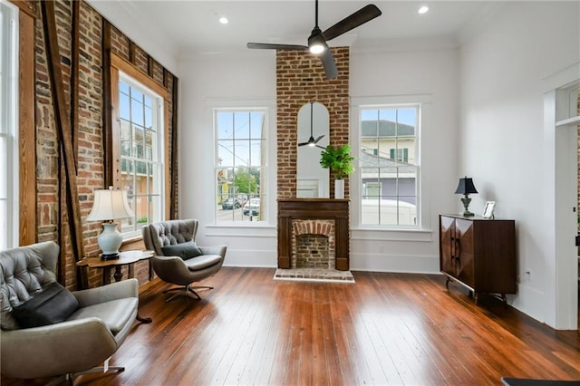 living area featuring a healthy amount of sunlight, dark hardwood / wood-style flooring, and a brick fireplace