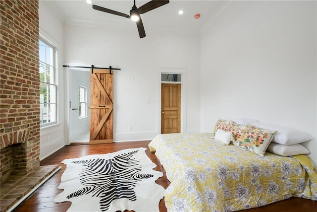 bedroom featuring ceiling fan, hardwood / wood-style flooring, crown molding, and a barn door