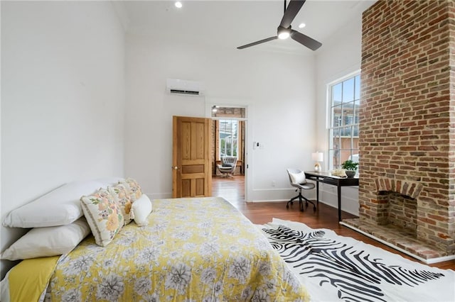 bedroom with dark wood-type flooring, ceiling fan, an AC wall unit, and multiple windows