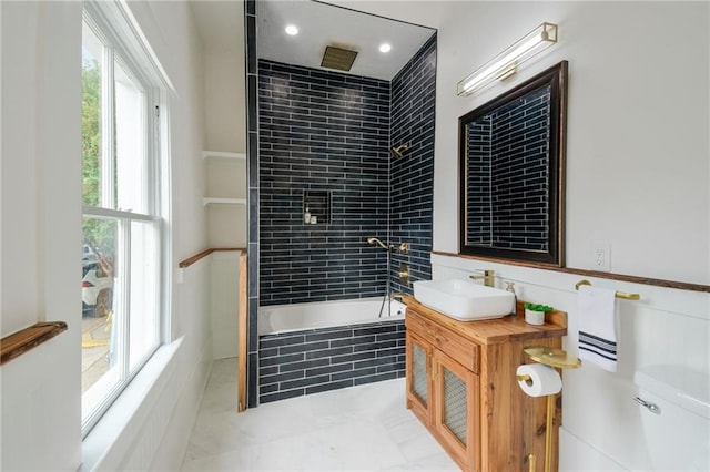 bathroom featuring a wealth of natural light, vanity, and tiled shower / bath combo