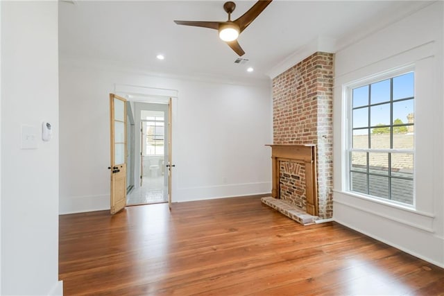 unfurnished living room featuring ceiling fan, hardwood / wood-style flooring, a wealth of natural light, and a fireplace