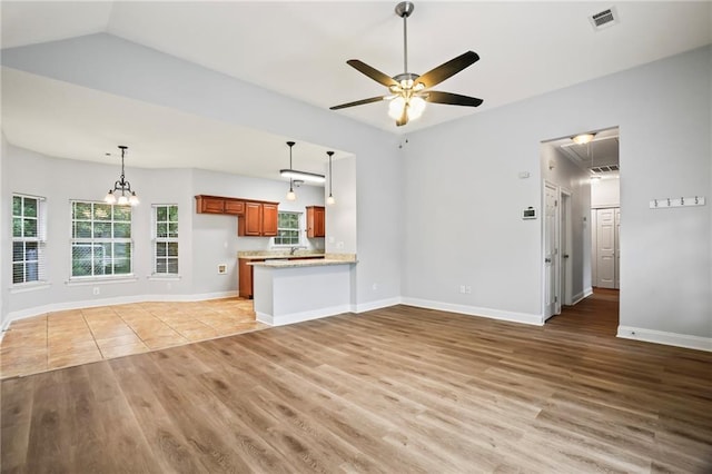 unfurnished living room featuring light wood-style floors, baseboards, ceiling fan with notable chandelier, and visible vents