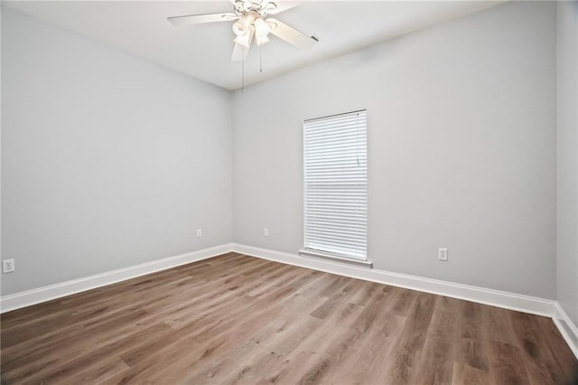 empty room with baseboards, ceiling fan, and wood finished floors